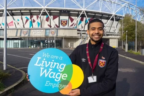 Man holding Living Wage Sign outside West Ham stadium