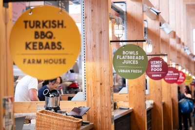 Several signs outside of foodstalls, they read 'turkish bbq kebabs', 'bowls, flapbreads, juices'